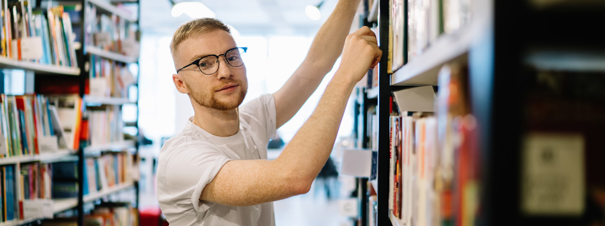 Young man searching bookshelves